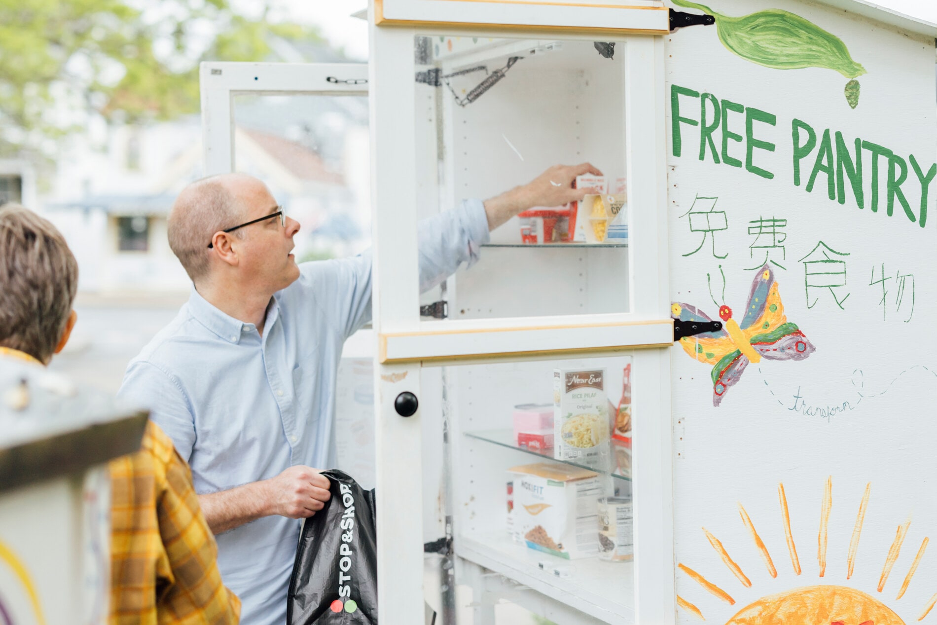 A man stocks a free food pantry in front of a church