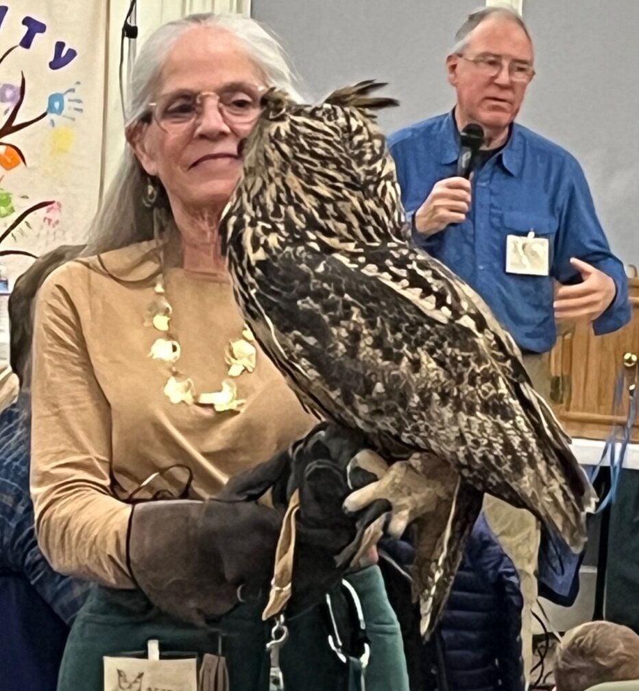 Woman with a large owl perched on her gloved hand.