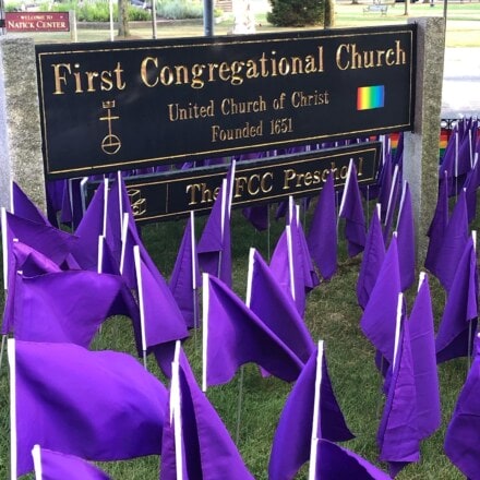 Church sign surrounded by many purple flags