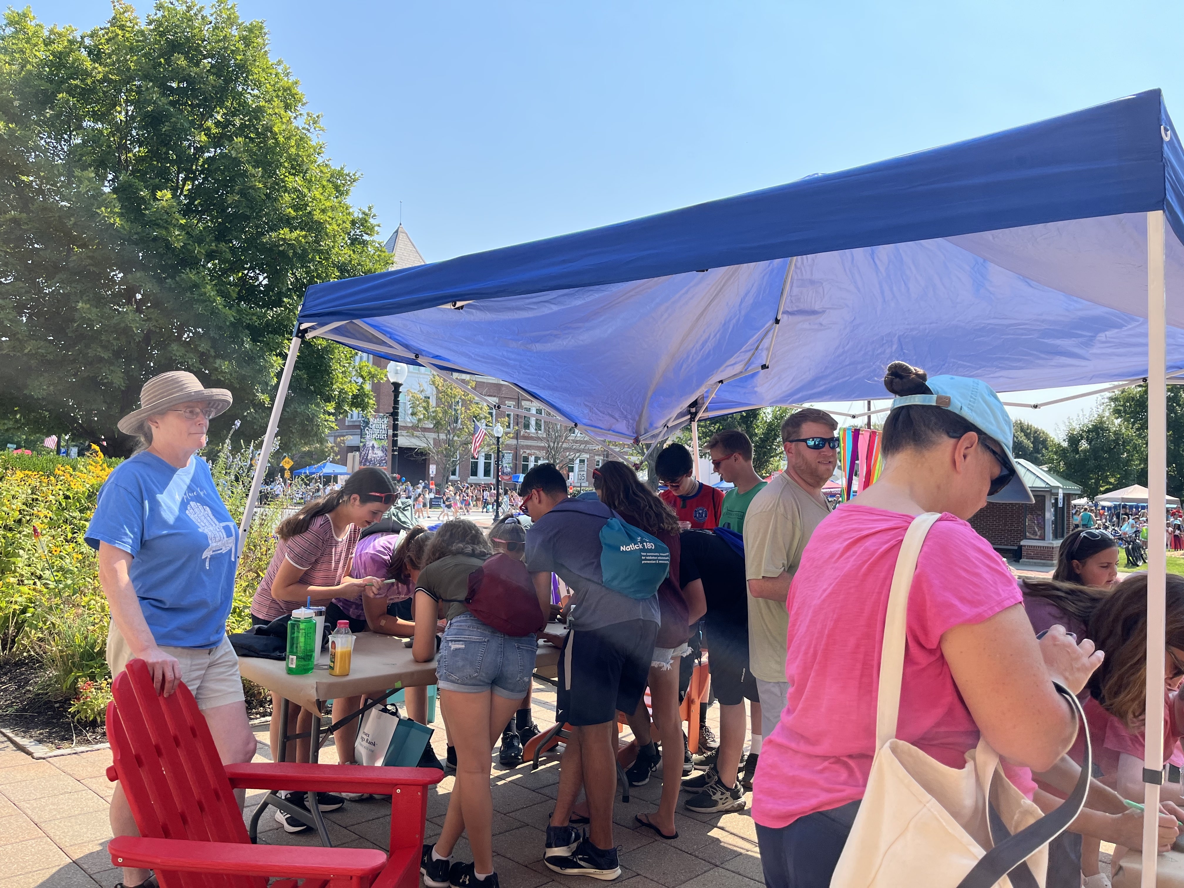 natick days 2022 3151 People doing an art project in an open air tent in front of the church.