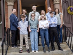 Four thirteen year olds and their parents posing on the front steps of a church.