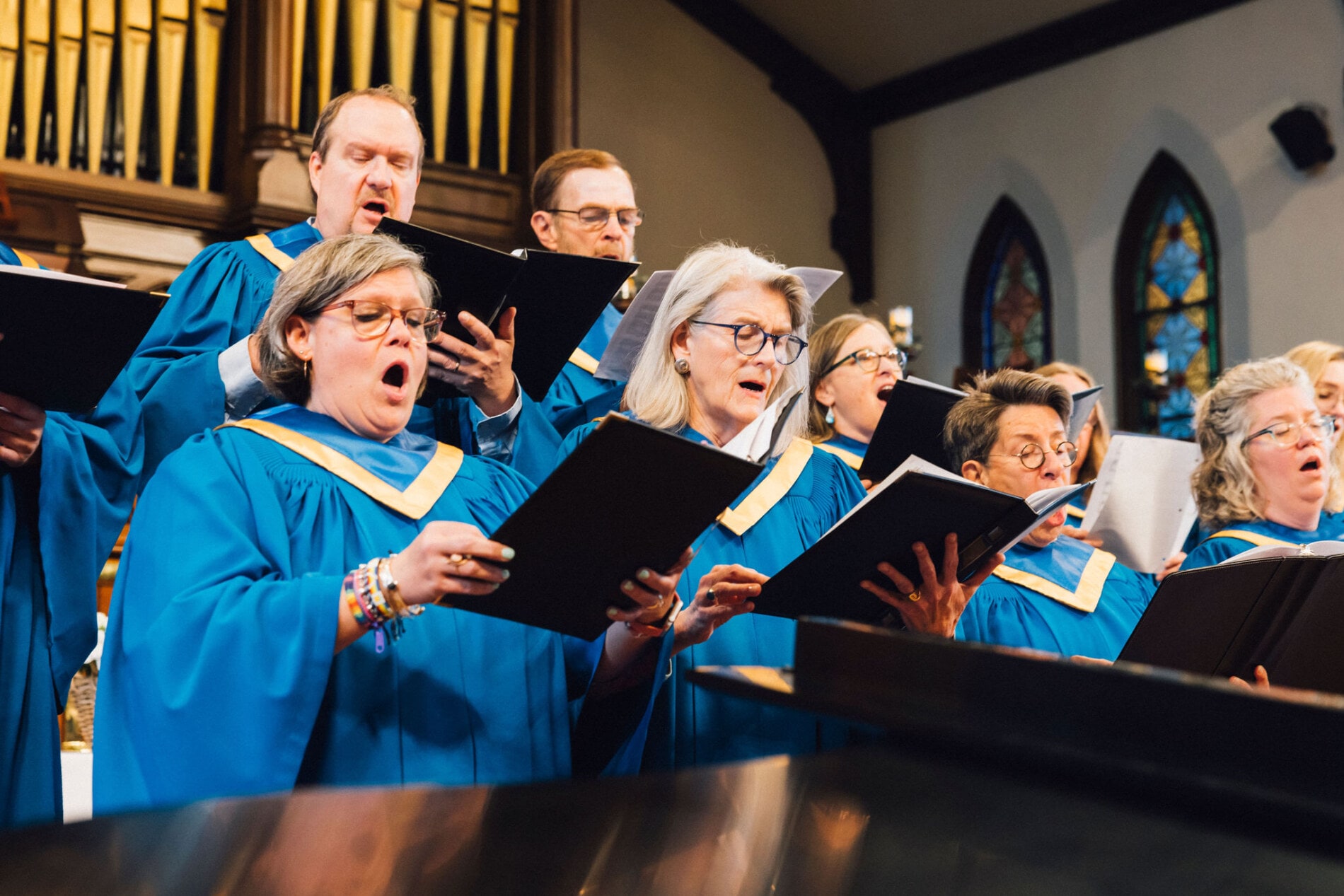 A choir singing. They wear blue choir robes.