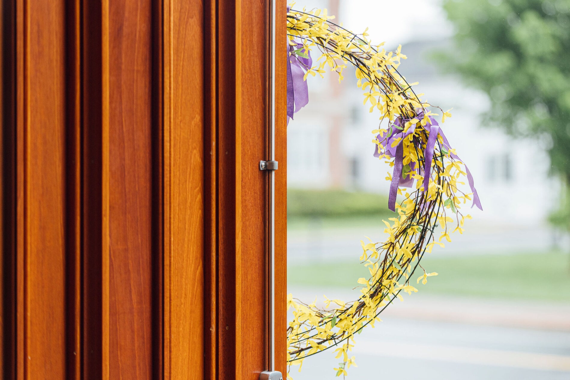 A wreath with purple and yellow flowers hangs on a church door