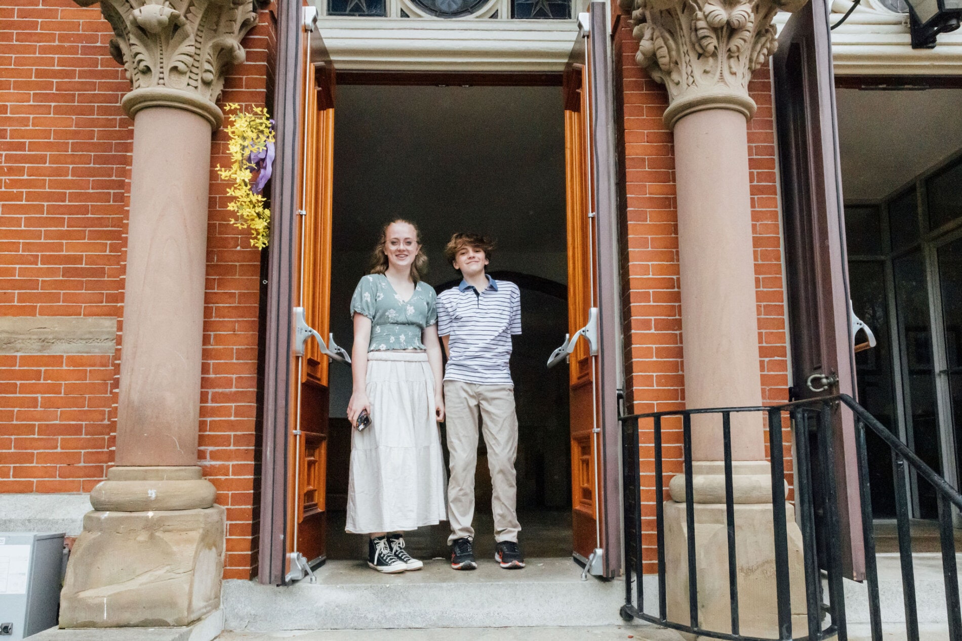 Two teenagers stand in the entrance to a church