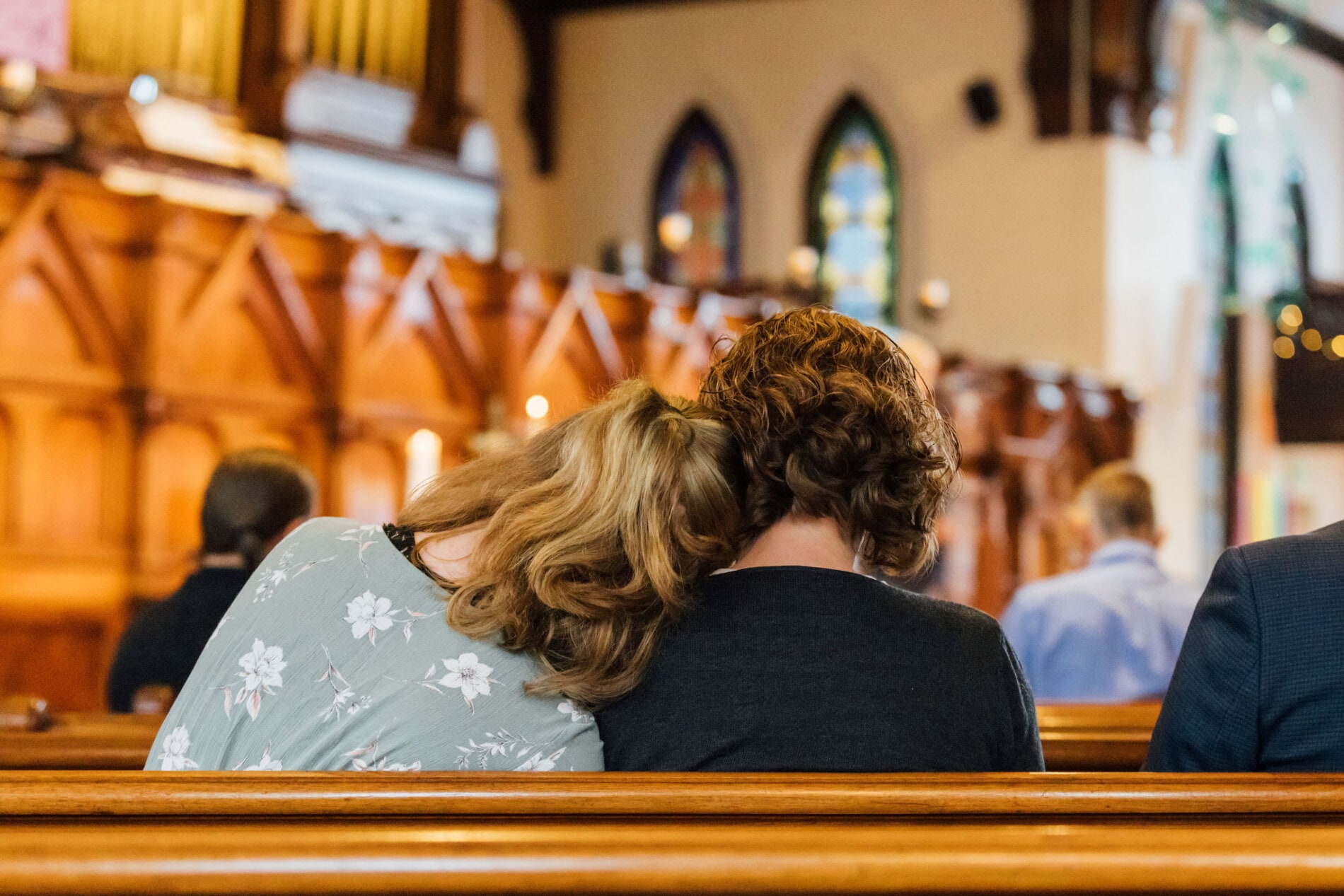 A person rests their head on the shoulder of another