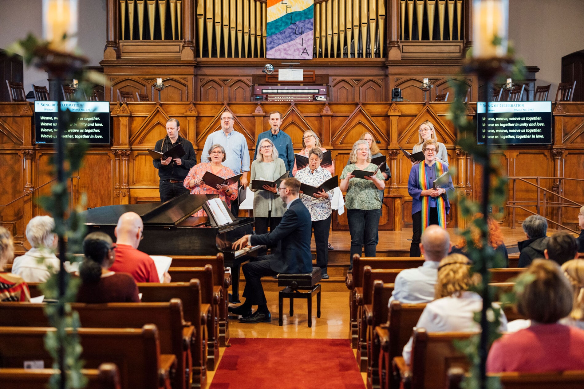 A choir sings while a man plays the piano