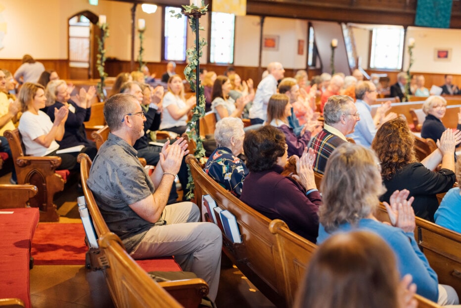 Congregation clapping while sitting in pews