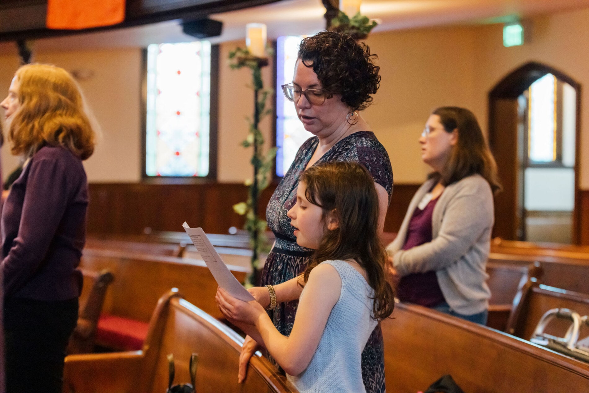 A mother and daughter sing a song in church