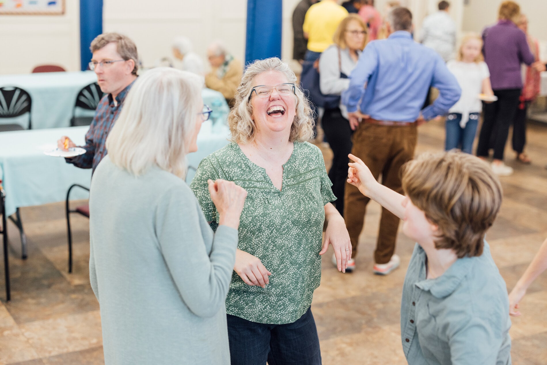 A woman laughs while a teenager points at her