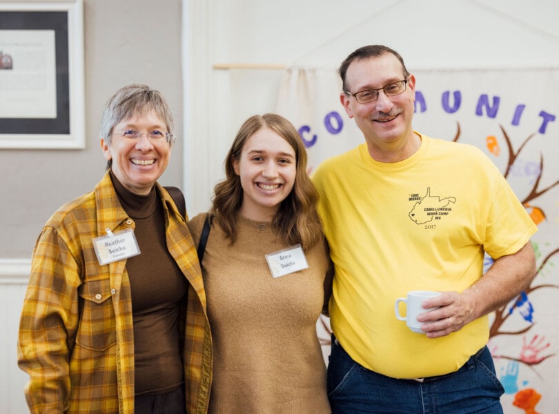 Two adults and a teenager with arms around one another