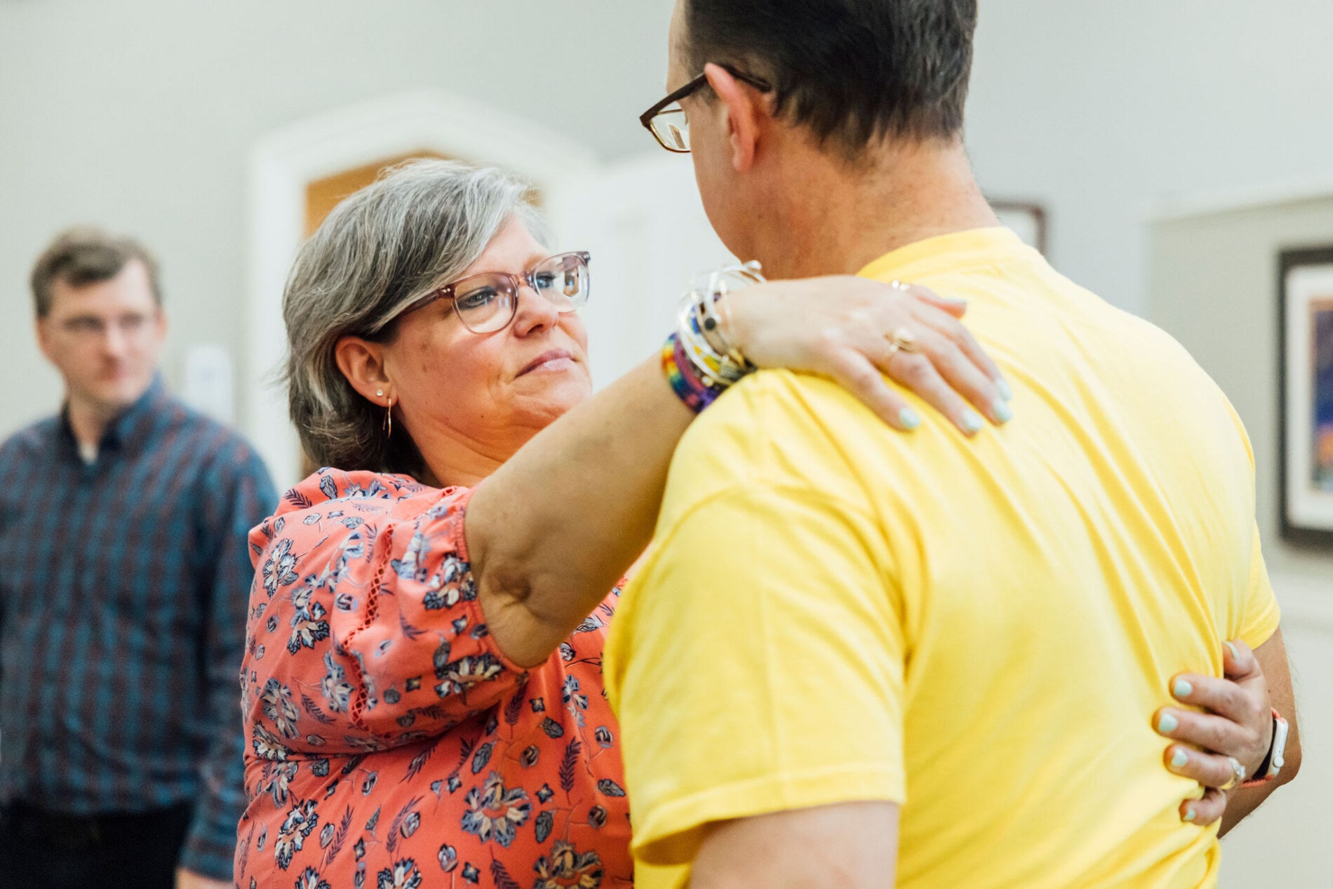 A woman lookin concerned and placing her hand on the shoulder of a man