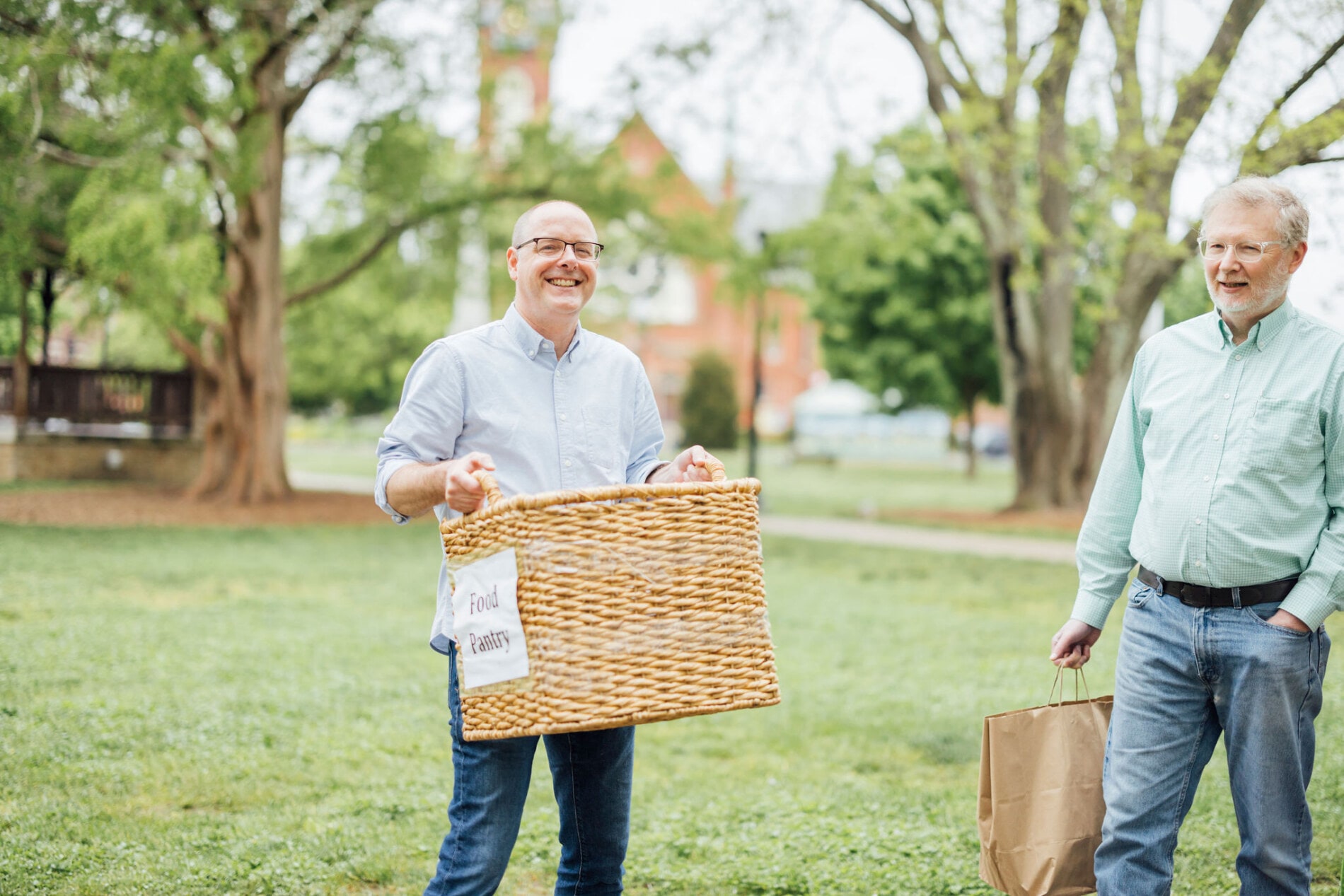 Two men carrying baskets of food for hungry people