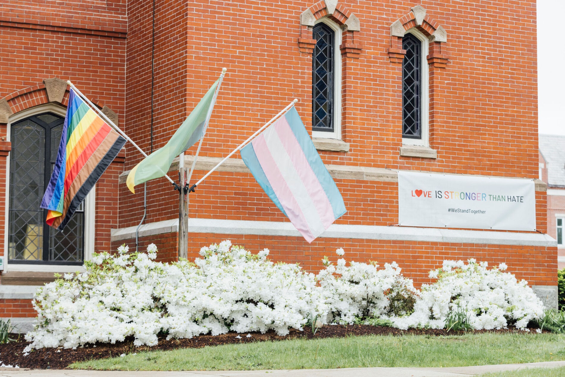 A brick church with Pride flags and a banner that reads "Love is Stronger Than Hate"