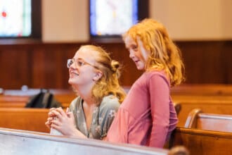 Two people smiling in the pews at church