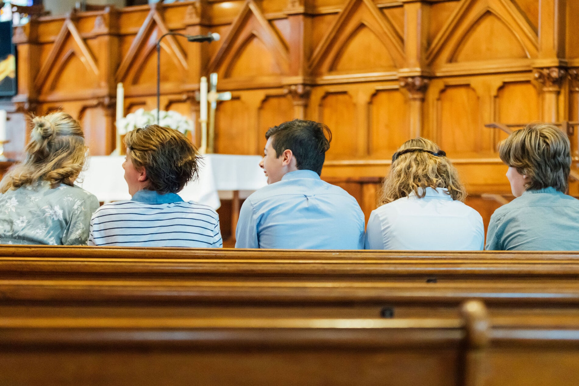 A group of teen sit on a church pew