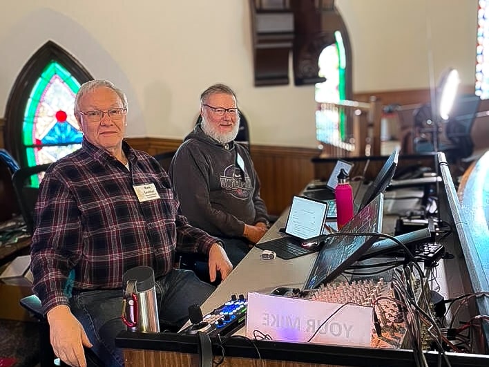 Two men sitting at an A/V console in a church