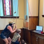 Mother and two young boys pulling a church bell rope.