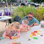 A father watches his two girls make leaf art.