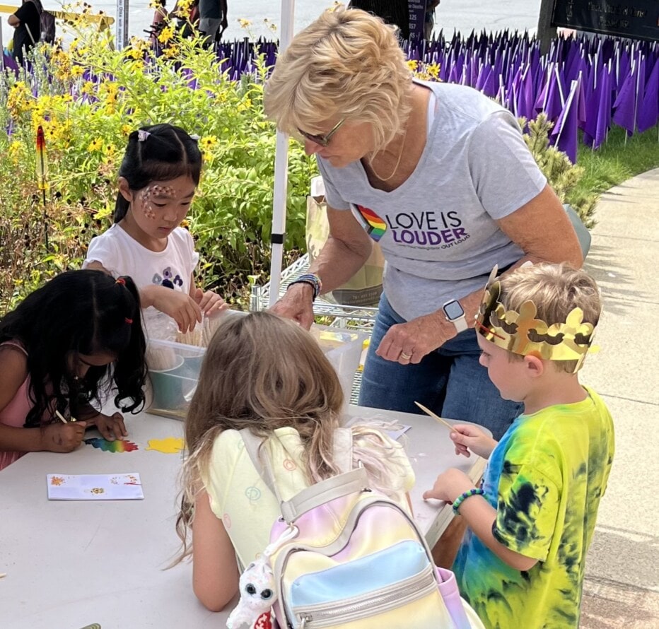 Woman helping four children with an art project.