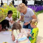 Woman helping four children with an art project.