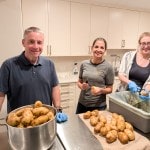 Three people ready to peel 30 lbs. of potatoes
