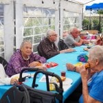 Several tables of people sit down to eat at the church barbeque.