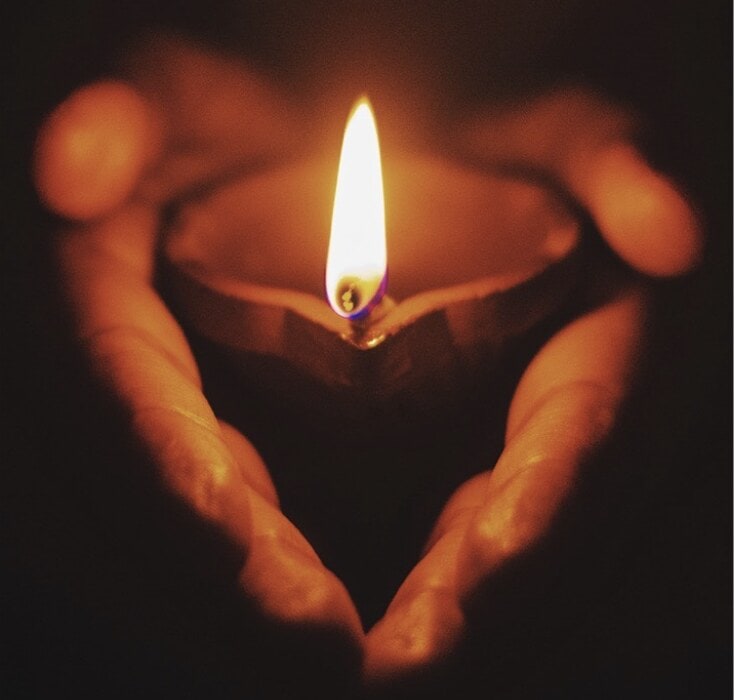 handscuppingcandle Two hands cupping a small light candle.