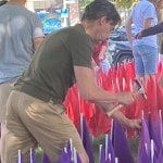 Man hammering purple flag into church lawn