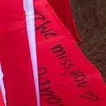 The words "We miss you" on a small red flag