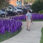 Young man with hammer walks past just installed purple flags