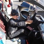 Boy in batman costume at the wheel of a full-sized batmobile