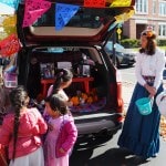 Woman in costume gives halloween treats to children.