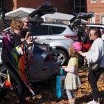 Woman in butterfly costume gives halloween candy to a girl