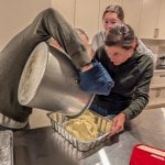 three people scooping mashed potatoes out of a pot