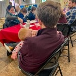 a baby asleep in father's arms during annual meeting in vestry